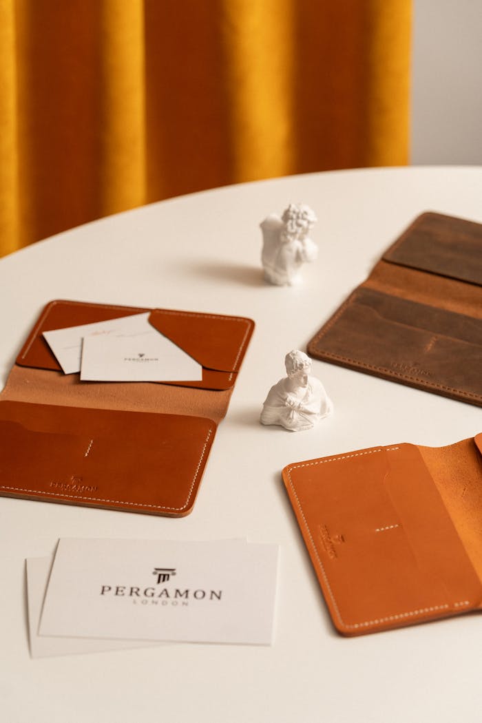 Stylish leather wallets and cardholders with art statues on a tabletop.