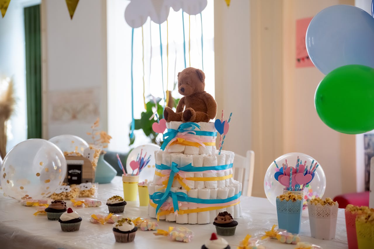 Adorable baby shower table with a diaper cake, teddy bear, cupcakes, and colorful decor.